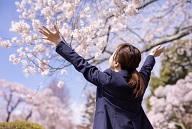 桜とスーツを着る女性